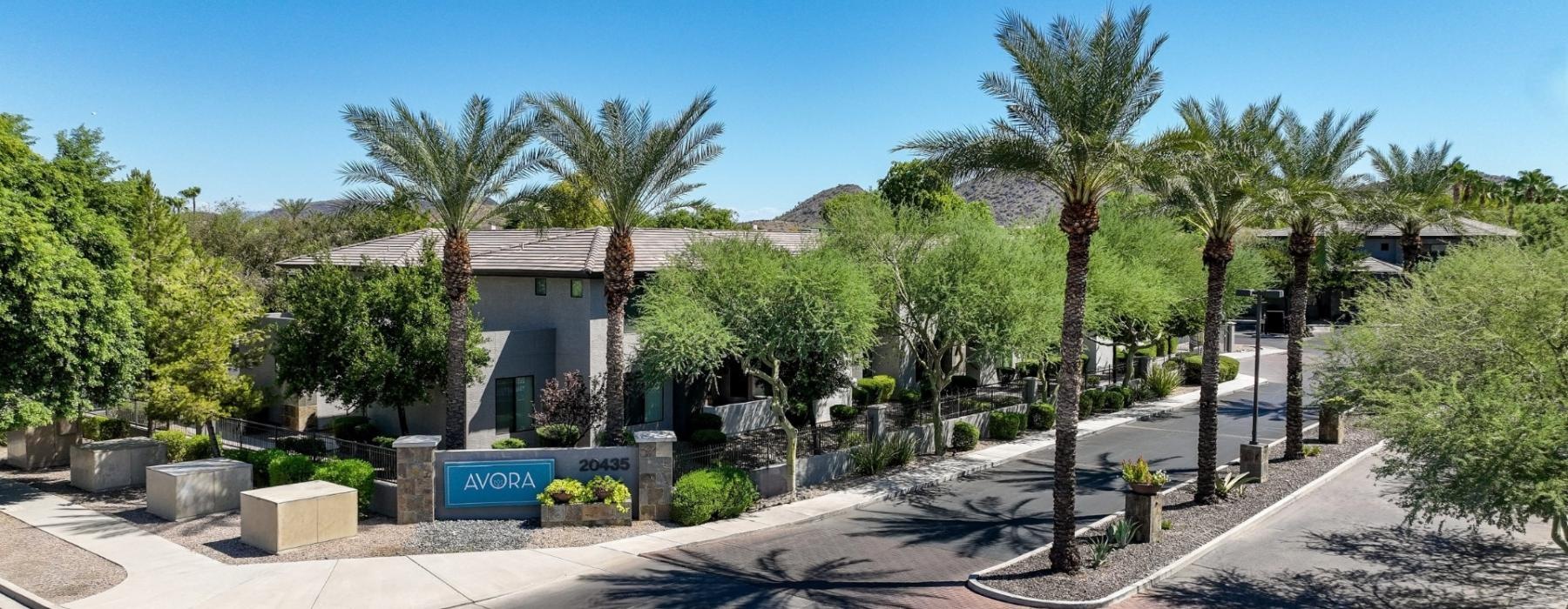 a building with palm trees and a sign in front of it